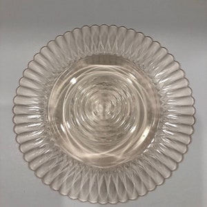 Puede incluir: Plato de vidrio transparente con borde festoneado. El centro del plato presenta c&iacute;rculos conc&eacute;ntricos. El plato es transparente y probablemente se utiliza para servir alimentos.