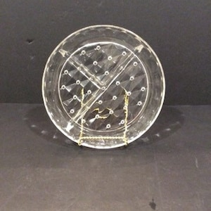 May include: A clear glass divided serving dish with a diamond pattern and small dots. The dish is on a gold stand.