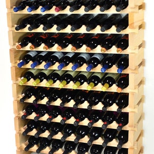 May include: A wooden wine rack filled with numerous wine bottles. The rack is made of light-colored wood and has multiple shelves, each holding several bottles. The bottles are dark, with colorful labels and foil tops. The rack is designed to store wine bottles horizontally.