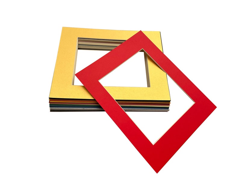 May include: A stack of colourful mat boards with a red mat board on top. The mat boards have a white core and a coloured outer layer. The mat boards are used for framing pictures and artwork.