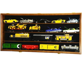 May include: A wooden display case filled with various model cars and train cars. The cars are in yellow, silver, black, and blue. The train cars are in yellow, green, red, and black. The case has a dark interior and a light brown wooden frame.