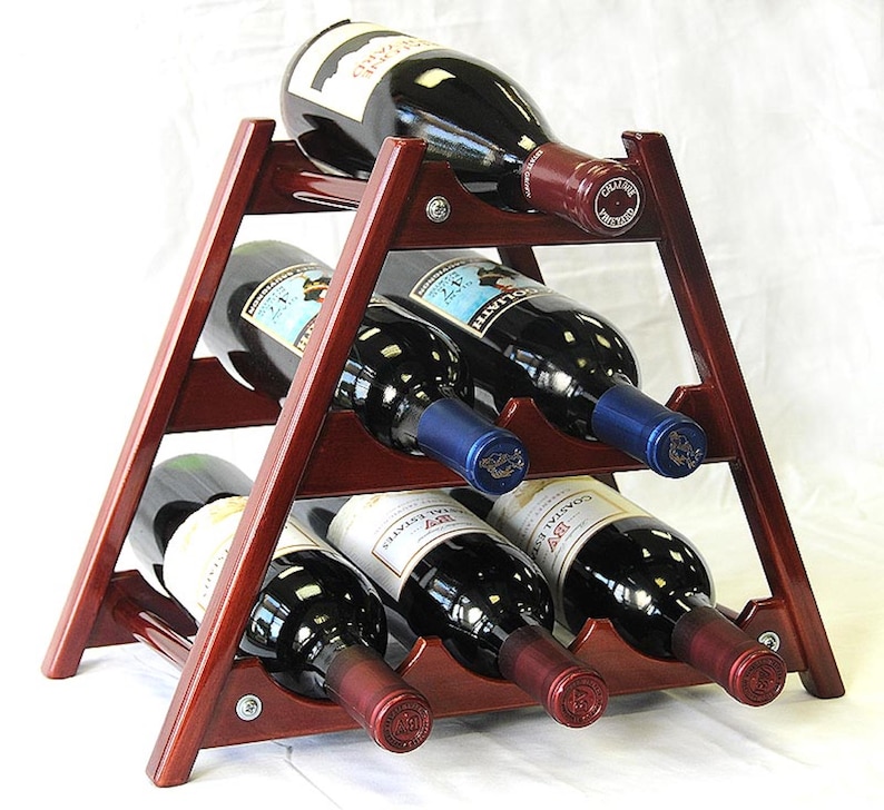 May include: A wooden wine rack with a triangular shape and six slots for bottles. The rack is made of dark wood and has a natural finish. The rack is filled with six bottles of wine, all with different labels.