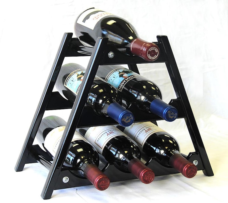 May include: Black triangular wine rack with six bottles of red wine. The rack is made of wood and has a modern design.