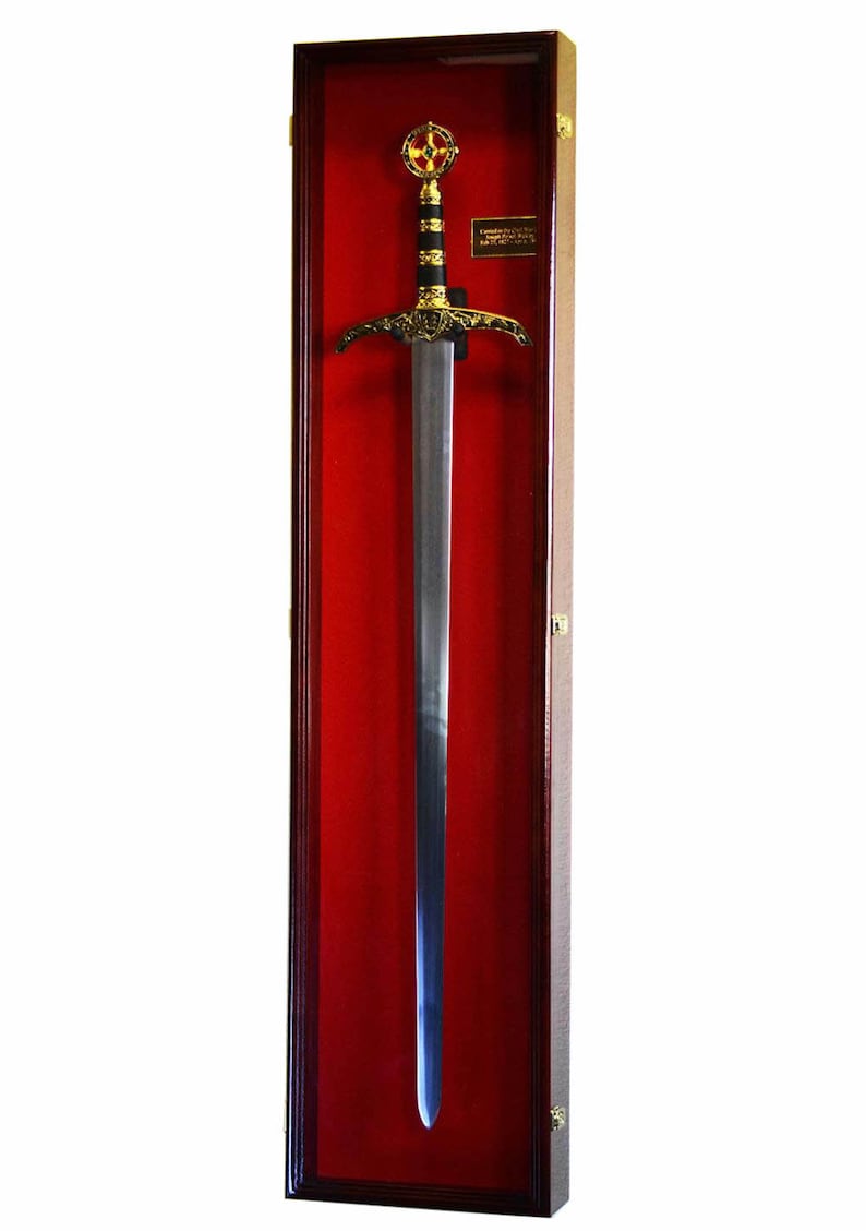 May include: A decorative sword in a wooden display case. The sword features a silver blade, a black and gold handle, and a gold cross-shaped hilt. The display case has a red velvet interior.