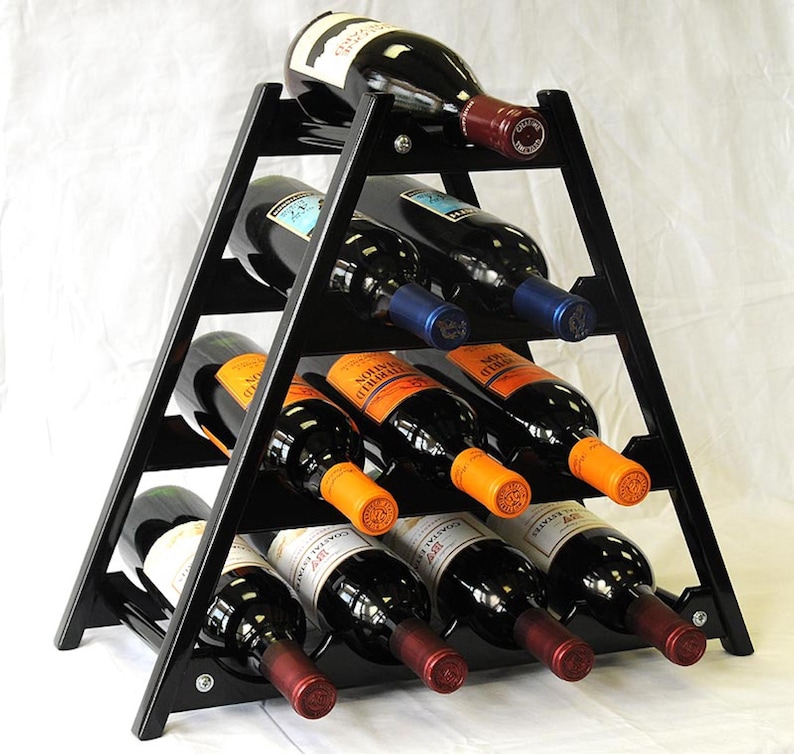 May include: Black wooden wine rack with a triangular shape and six shelves. The rack is filled with bottles of wine, some with orange labels and some with blue labels.
