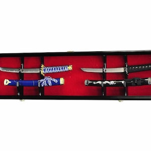 May include: Black wooden display case with red velvet lining, showcasing four swords with intricate details. The swords are displayed on black velvet stands.