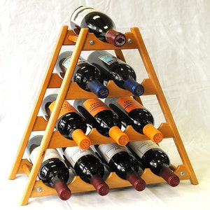 May include: A wooden wine rack with a triangular shape, holding nine bottles of wine. The rack is made of light brown wood and has a natural finish. The bottles are arranged in three rows, with three bottles in each row. The bottles are all different colors and have different labels.