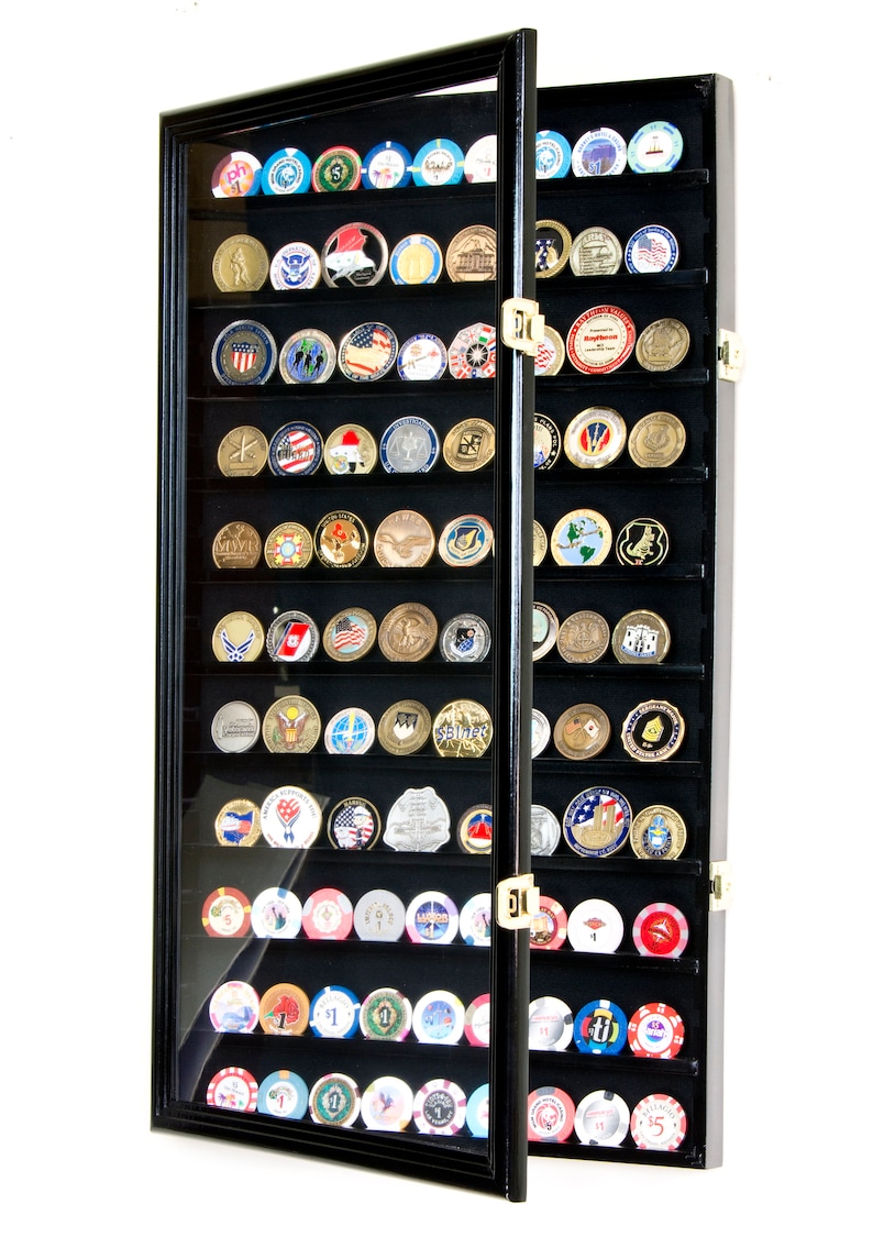 May include: Black wooden display case with glass doors for storing and displaying coins or challenge coins. The case has 36 slots and is open to reveal the coins inside.