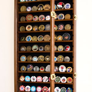 May include: A wooden display case with glass doors for storing and displaying coins or tokens. The case has 18 shelves and is filled with a variety of coins and tokens.