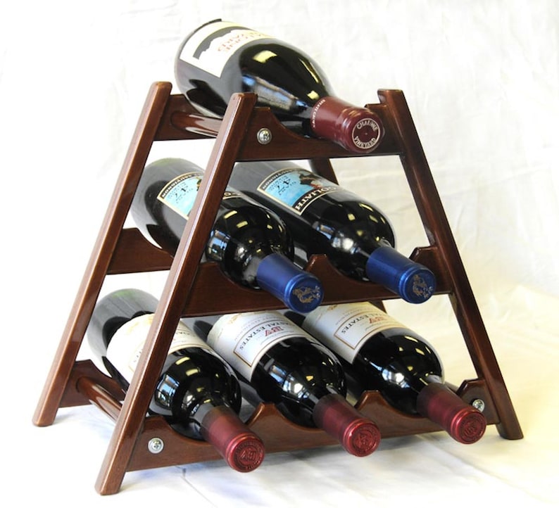 May include: A wooden wine rack with a triangular shape and six slots for bottles. The rack is made of dark brown wood and has a natural finish. The rack is holding six bottles of wine, all of which are red wine.