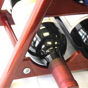 May include: A wooden wine rack with two bottles of red wine. The bottles are partially visible, with the labels and the tops of the bottles showing. The rack is made of dark wood and has a simple design.