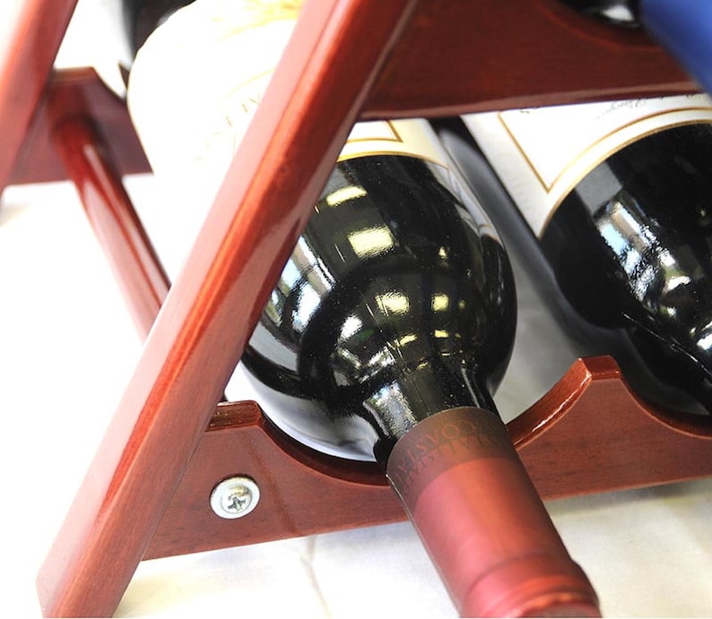 May include: A wooden wine rack with two bottles of red wine. The bottles are partially visible, with the labels and the tops of the bottles showing. The rack is made of dark wood and has a simple design.