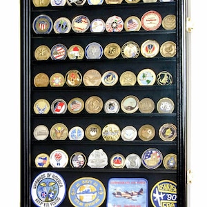 May include: Black shadow box display case with glass front and black felt lining. The case is filled with rows of military challenge coins and patches. The patches include the text "Warbirds of America Keep 'em Flying", "19 Navy 82 It's an Adventure", "Confederate Air Force", "Oshkosh '90 EAA", "Oshkosh '86 EAA", "The Essential Link NAF", and "USS Intrepid".