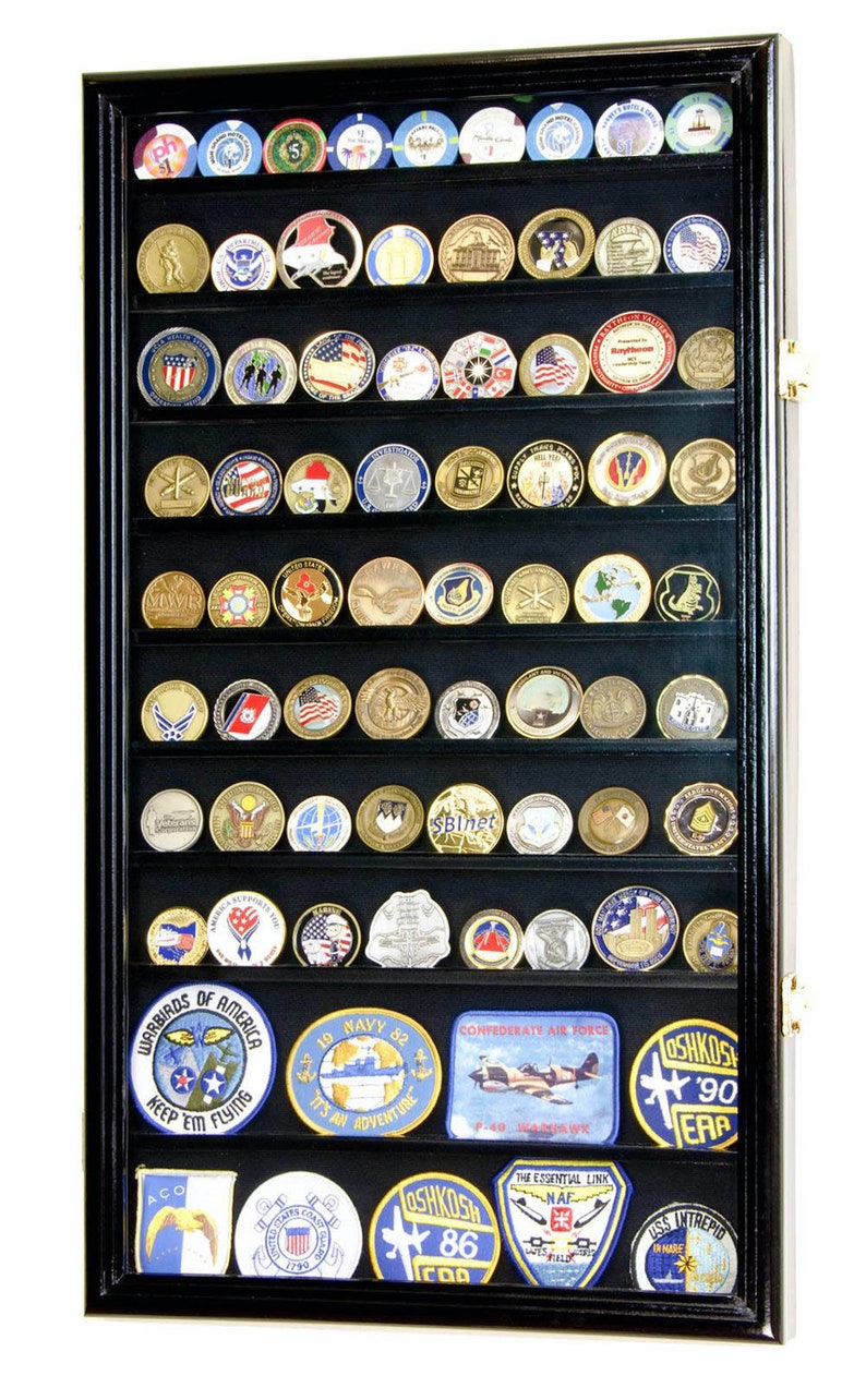 May include: Black shadow box display case with glass front and black felt lining. The case is filled with rows of military challenge coins and patches. The patches include the text "Warbirds of America Keep 'em Flying", "19 Navy 82 It's an Adventure", "Confederate Air Force", "Oshkosh '90 EAA", "Oshkosh '86 EAA", "The Essential Link NAF", and "USS Intrepid".