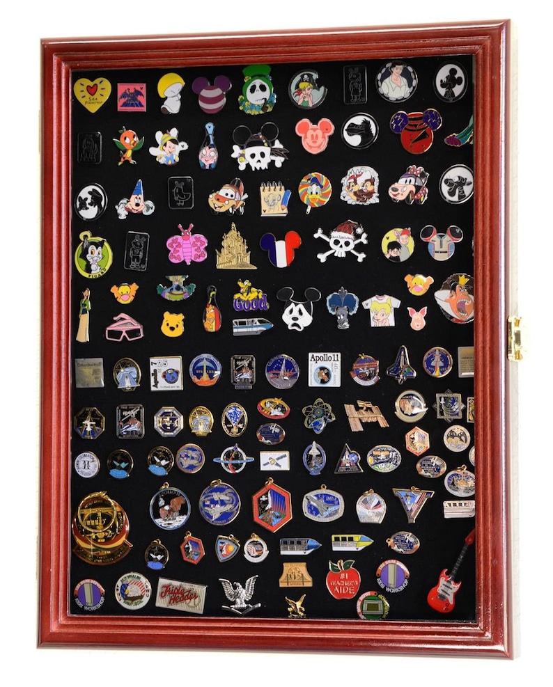May include: A red wooden shadow box display case with a black felt background filled with a variety of colorful enamel pins. The pins feature various themes including cartoon characters, space exploration, and transportation.