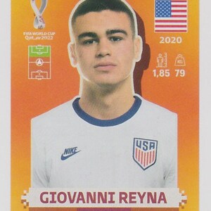 Puede incluir: Una tarjeta coleccionable de Giovanni Reyna, jugador de f&uacute;tbol de EE. UU. La tarjeta incluye la bandera de EE. UU., el logotipo de Nike y el logotipo de la Copa Mundial de la FIFA Qatar 2022. La altura del jugador es de 1,85 metros y pesa 79 kg.