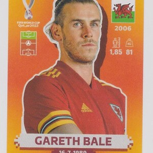 Puede incluir: Tarjeta coleccionable de Gareth Bale con camiseta roja. Muestra el logo de la Copa Mundial de la FIFA Qatar 2022, la bandera galesa e informaci&oacute;n del jugador: 1,85 m, 81 kg, y fecha de nacimiento 16-7-1989.