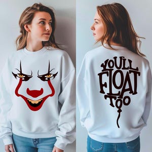 May include: White sweatshirt featuring a clown face design on the front with red, black, and yellow details. The back of the sweatshirt has the text "YOU'LL FLOAT TOO" in a balloon shape.
