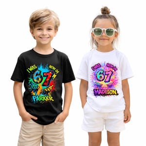 May include: Two children wearing matching birthday t-shirts. One shirt is black, the other white. Both shirts have the text "I WAS NOW I'M 67" with a colorful splash design and a name below. The black shirt says "Parker", the white shirt says "Madison".