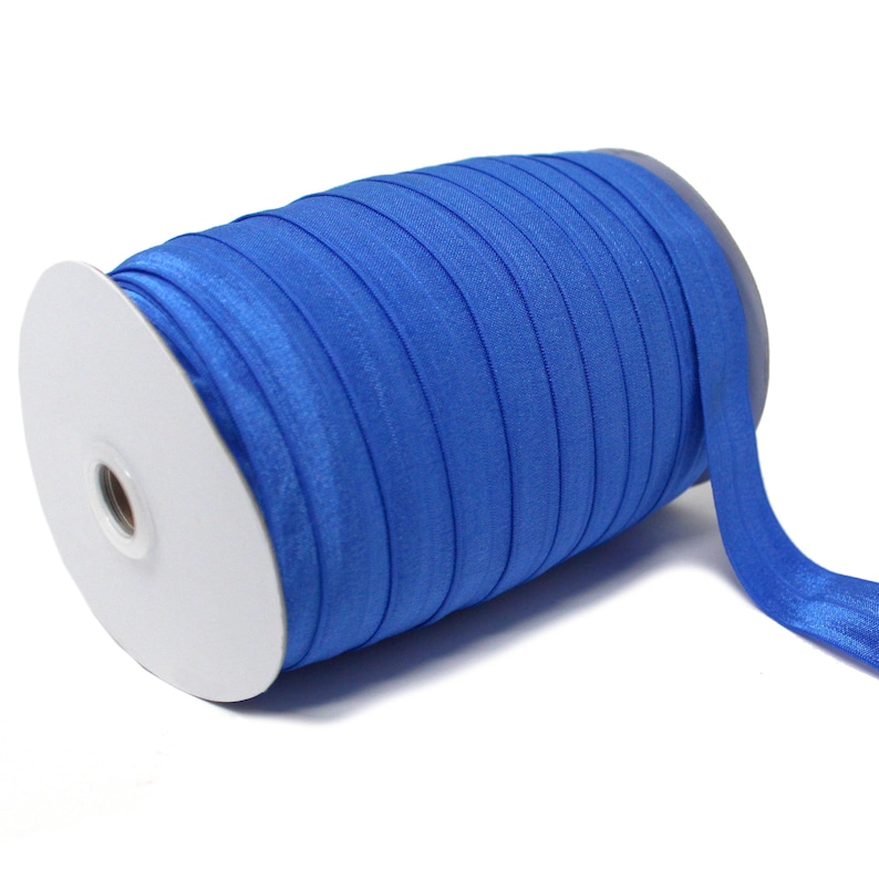 Op de afbeelding: Een rol helderblauw elastisch lint, gewikkeld om een witte kartonnen spoel.