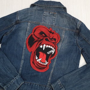 May include: A blue denim jacket with a red embroidered gorilla head patch on the back.