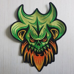 May include: Green and orange embroidered patch of a skull with horns and a beard of flames.