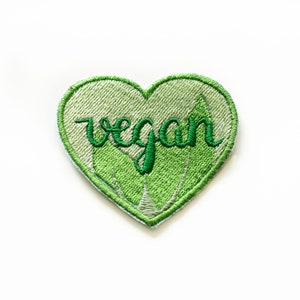 Può includere: Toppa a forma di cuore verde con la parola "vegan" ricamata in verde.