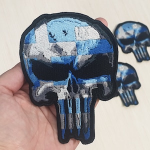 May include: A blue and white embroidered skull patch with a Punisher skull design. The skull is made of a blue and white fabric with a black background.