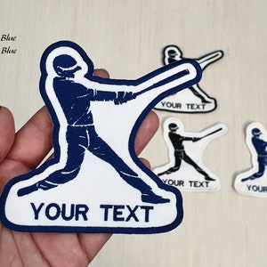 Puede incluir: Un parche blanco para planchar con una silueta azul de un jugador de béisbol sosteniendo un bate. El parche tiene un borde azul y el texto "YOUR TEXT" en azul.