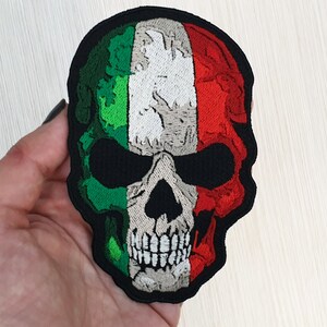 May include: Embroidered patch of a skull with the Italian flag colours of green, white, and red.