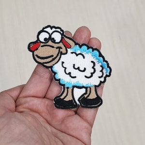 May include: A white sheep with blue accents and a brown face, with big eyes and a smile, is embroidered on a patch.