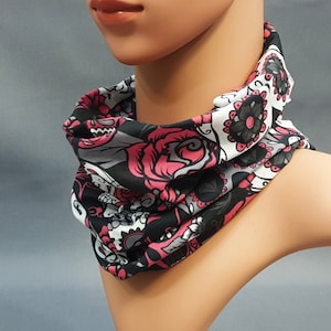 Puede incluir: Un pasamontañas estampado en negro, blanco y rosa con un diseño de calavera de azúcar.