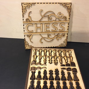 May include: A wooden chess set with a decorative lid that says "CHESS" in a stylized font. The set is open and the pieces are visible in their slots.