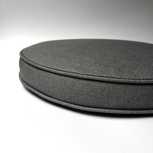 May include: A round gray fabric chair cushion with a thick, stitched edge.