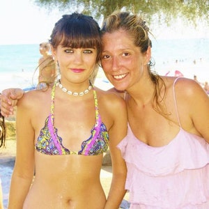 Könnte beinhalten: Zwei Frauen am Strand, eine trägt ein rosa Rüschenoberteil und die andere ein buntes Bikinioberteil mit einer Muschelkette.
