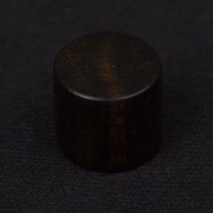 Peut inclure: Un objet cylindrique brun foncé, possiblement un bouton de meuble ou un élément décoratif, est centré sur un fond noir. L'objet a un dessus lisse et arrondi et une surface légèrement texturée, suggérant un matériau en bois ou en métal.