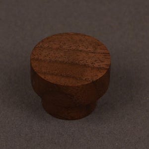 May include: A white ceramic mug with a black handle and the text "But First, Coffee" in a black, handwritten-style font. The mug is on a white surface.