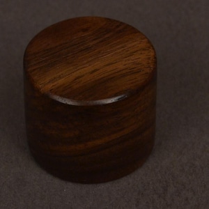 Peut inclure: Objet cylindrique en bois avec une finition marron foncé polie. Le grain du bois est visible sur la surface supérieure. L'objet est probablement un élément décoratif ou un composant d'un produit plus grand.