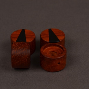 Peut inclure: Quatre boutons en bois brun rouge&acirc;tre. Chaque bouton cylindrique a un dessus plat avec une incrustation triangulaire noire. Un bouton a un petit trou. Ils sont probablement destin&eacute;s aux meubles ou &agrave; un usage d&eacute;coratif.