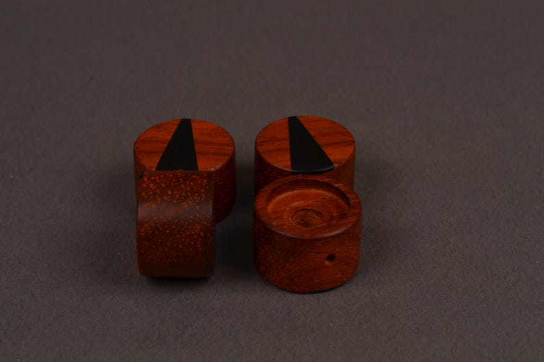 Peut inclure: Quatre boutons en bois brun rouge&acirc;tre. Chaque bouton cylindrique a un dessus plat avec une incrustation triangulaire noire. Un bouton a un petit trou. Ils sont probablement destin&eacute;s aux meubles ou &agrave; un usage d&eacute;coratif.