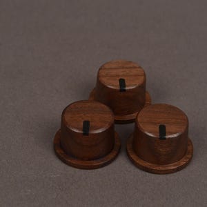 May include: Three cylindrical wooden control knobs with a dark brown wood grain finish. Each knob features a flat top surface with a single vertical black indicator line running from the center toward the outer edge of the circular top.