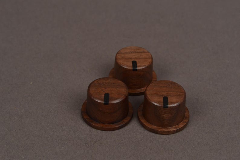 May include: Three cylindrical wooden control knobs with a dark brown wood grain finish. Each knob features a flat top surface with a single vertical black indicator line running from the center toward the outer edge of the circular top.