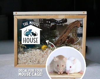 May include: A white decal with the text "The Mouse House" and a silhouette of two mice. The decal is on a wooden mouse cage with wood shavings and a water bottle.