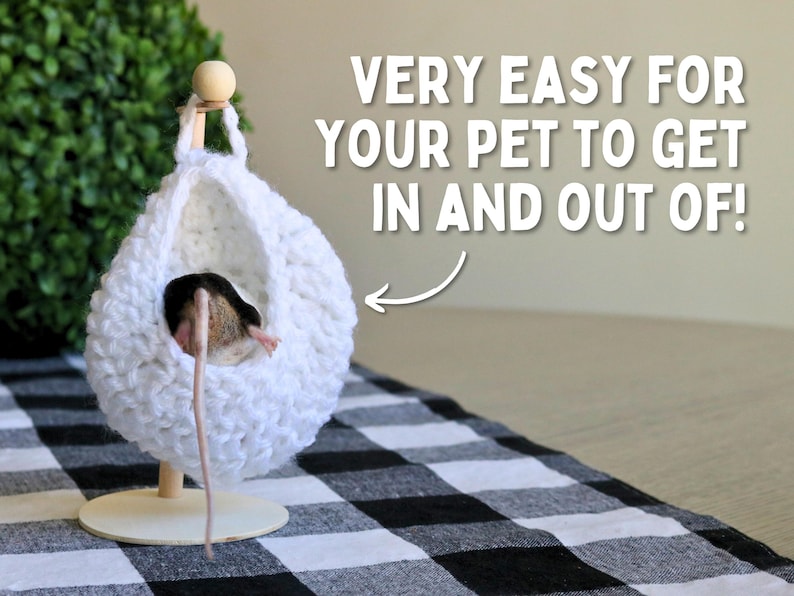 May include: A white crocheted hanging bed for small pets, like a mouse, with a wooden stand. The bed is suspended from a wooden dowel and has a round opening for easy access. The text "VERY EASY FOR YOUR PET TO GET IN AND OUT OF!" is visible in the image.