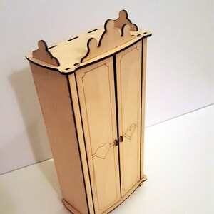 May include: A wooden dollhouse wardrobe with two doors, a crown-shaped top, and heart-shaped details on the doors.