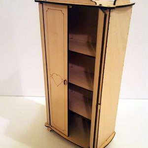 May include: A wooden dollhouse wardrobe with a single door that is open. The wardrobe has three shelves inside and a heart-shaped cutout on the door. The wardrobe is painted a light wood color and has a black outline.