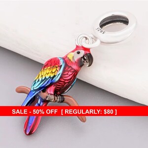 May include: A colorful parrot charm with red, yellow, blue, and pink plumage, perched on a brown branch. The charm has a silver loop with the text "S925". The parrot is a vibrant piece of jewelry.
