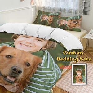 Puede incluir: Juego de cama personalizado con un niño sonriente y un golden retriever. El juego incluye una funda nórdica y dos fundas de almohada, todas con una impresión fotográfica personalizada. El texto "Custom Bedding Sets" es visible.