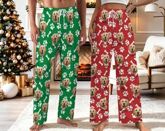 May include: Two pairs of lounge trousers featuring a repeating pattern of golden retriever faces and white paw prints. One pair is green with white drawstring ties, and the other pair is red with white drawstring ties. Each dog face is labelled Molly.