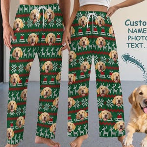 Puede incluir: Pantalones de pijama verdes con un patrón repetido de caras de golden retriever, copos de nieve y renos. Los pantalones tienen un diseño de punto rojo y blanco y una cintura con cordón. El texto "Custom NAME/ PHOTO TEXT..." es visible.